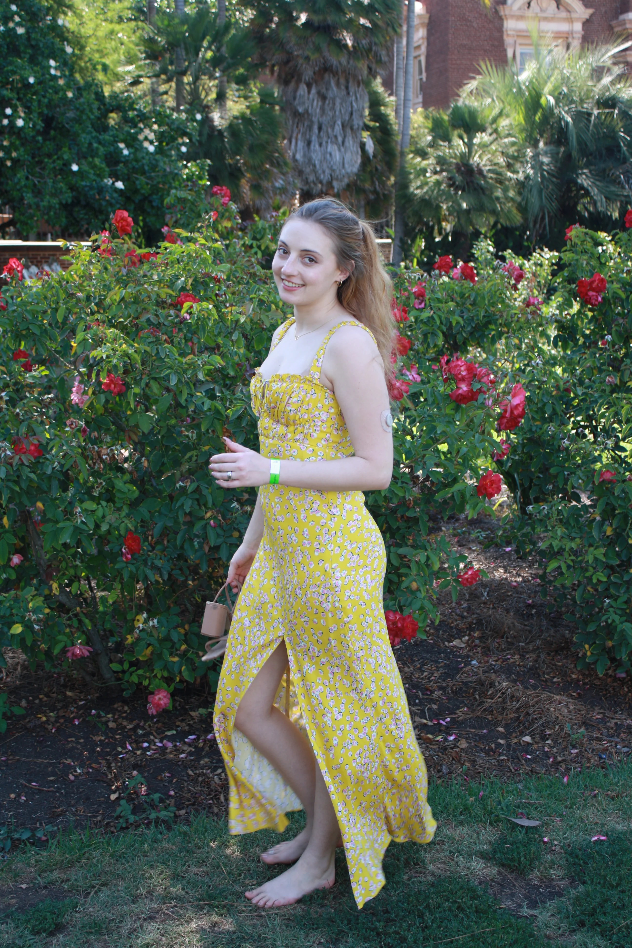 Jordie Morris standing barefoot beside a red rose bush at the Exposition Park Rose Garden.